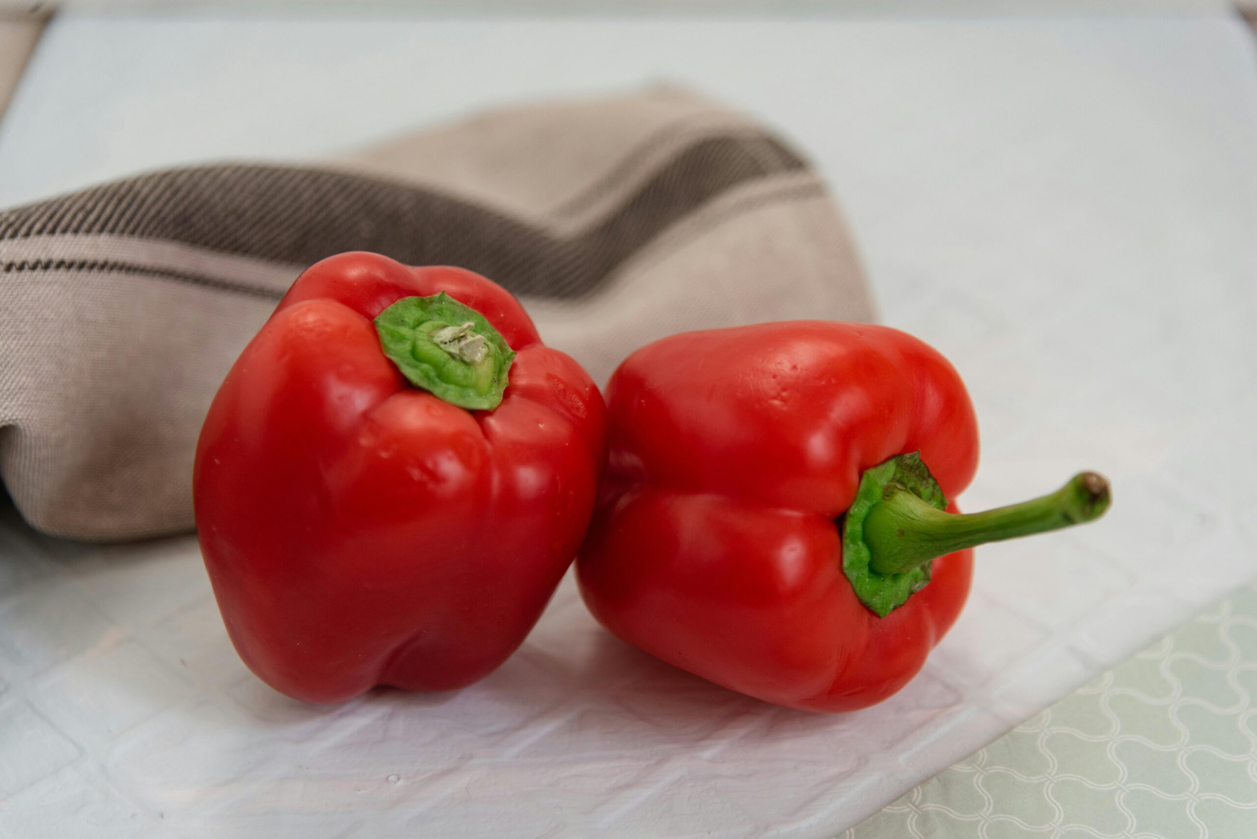 Fresh red bell peppers with napkin on kitchen table, highlighting vibrant color and healthy nutrition.